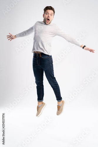 Full-length photo of funny man 30s in casual t-shirt and jeans jumping isolated over white background.