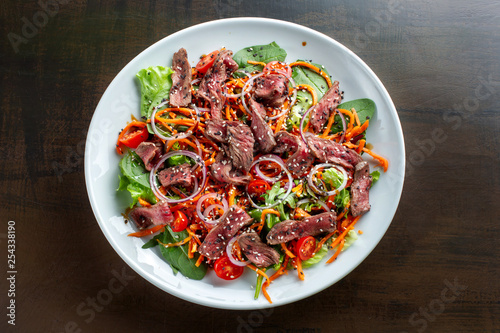 Beef salad sprinkled with sesame and garnished with onion rings.