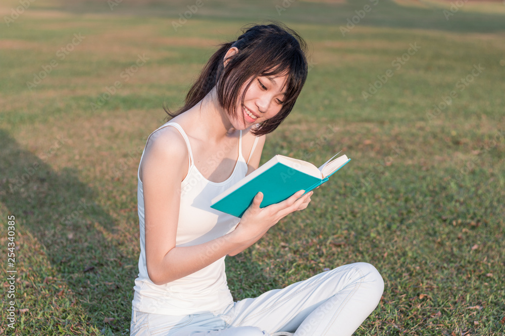 Obraz premium young woman reading a book in the park