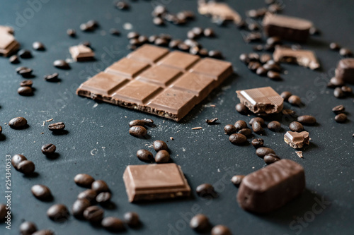 flat lay of chocolate bar with sweets and coffee beans on dark background