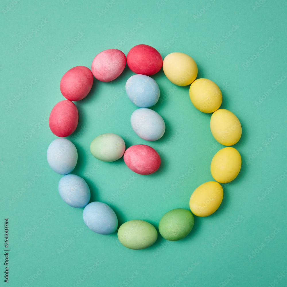 Different colored eggs in the shape of a clock on a green background with copy space. Flat lay Different colored eggs in the shape of a clock on a green background with copy space. Flat lay
