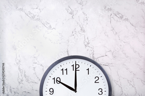 Wall clock on white marble texture with copyspace. Office clock on marble background