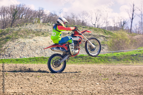 Fototapeta Naklejka Na Ścianę i Meble -  biker on motorcycle stunts while driving on the rear wheel side view