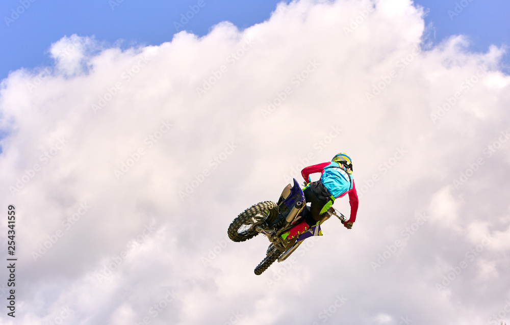 Fototapeta premium Motocross Rider Jump in a blue sky with clouds