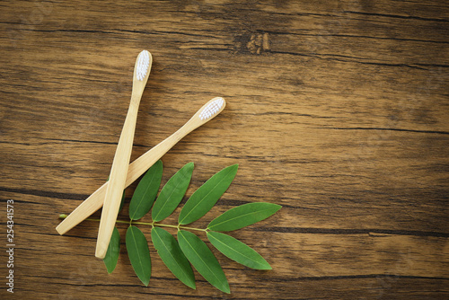 Zero waste Bathroom use less plastic concept / bamboo toothbrush and green leaf on rustic background