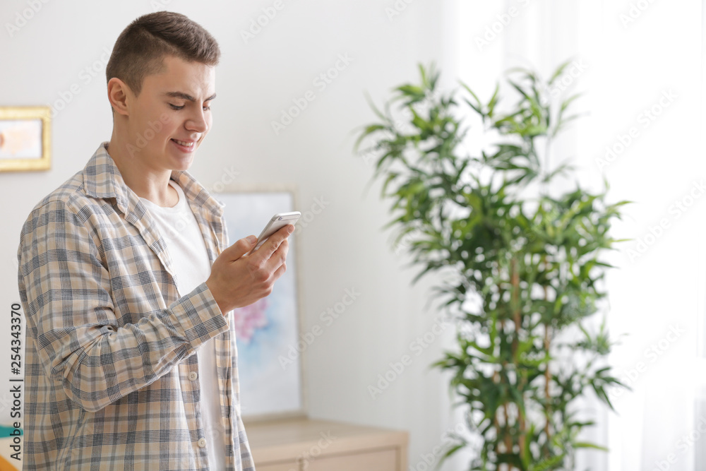 Teenage boy with mobile phone in room. Modern technology and smart home automation Teenage boy with mobile phone in room. Modern technology and smart home automation