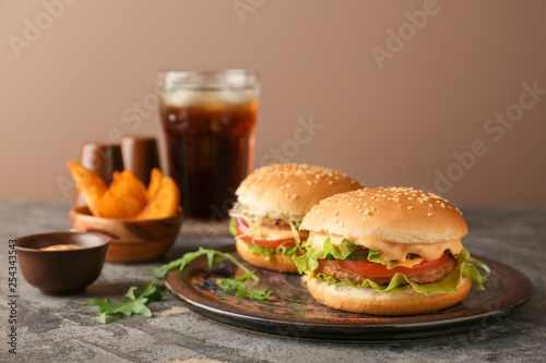 Plate with tasty burgers on table