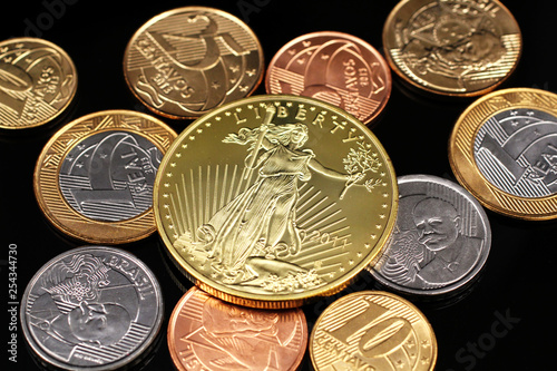 Fotografía A macro image of miscellaneous Brazilian coins with a American one ounce gold pa