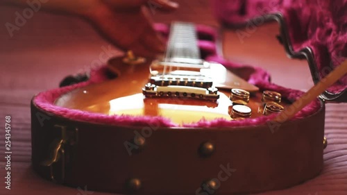 Man pulling out a guitar out of case and putting back. Closeup
