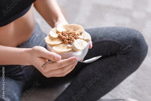 Fototapeta Naklejka Na Ścianę i Meble -  Sporty woman eating tasty yogurt at home, closeup