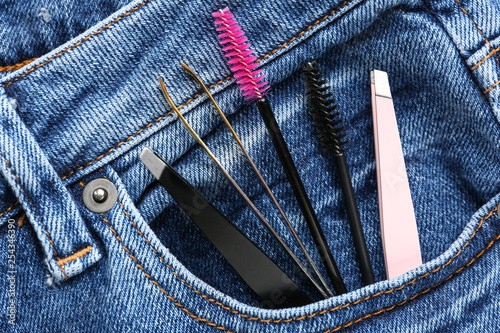 Set of tools for eyebrows correction in jeans pocket, closeup photo