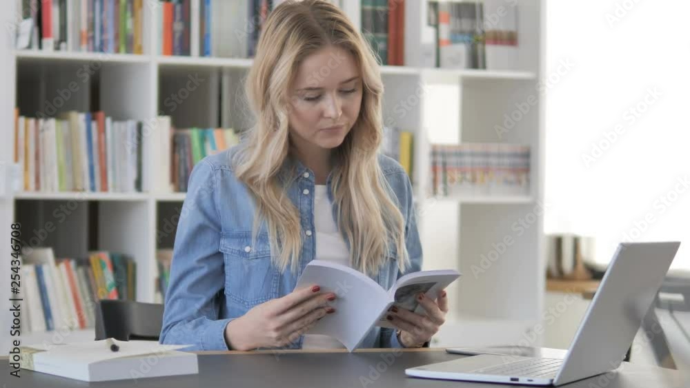 Young Woman Reading Book in Library Young Woman Reading Book in Library