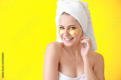 Young woman with under-eye patches on color background