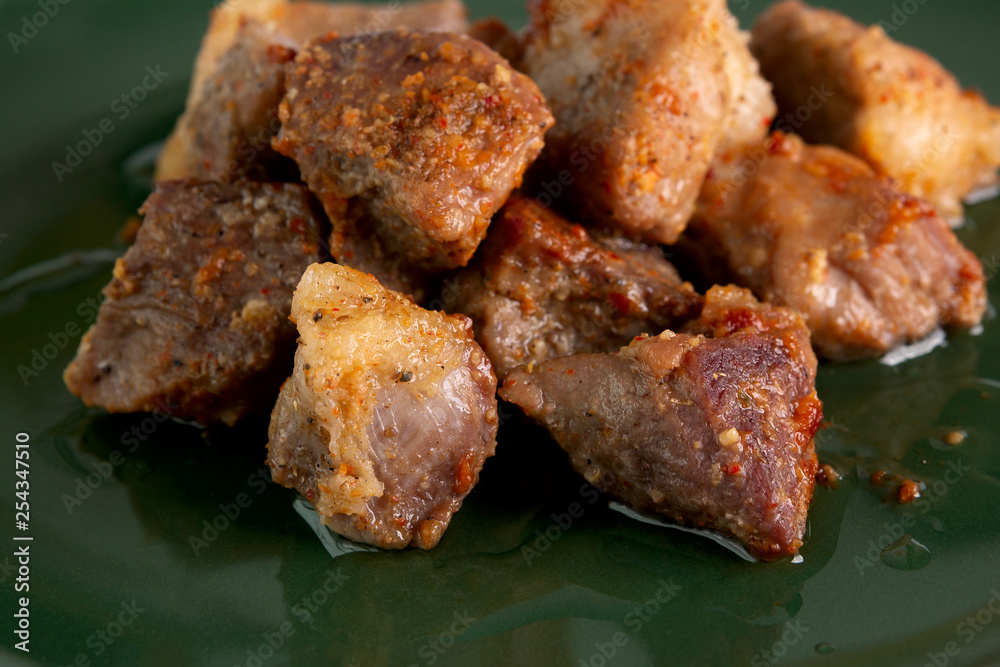 Hot pork slices. Delicious baked crispy pork slices have a crisp beautiful color and pickles lie in a green dish. Mouth-watering and delicious freshly cooked meat food.