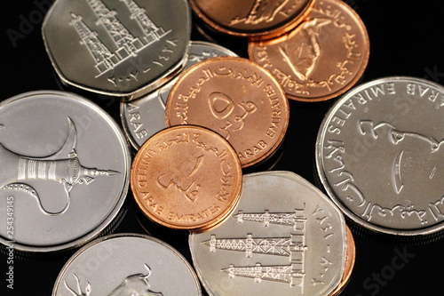 A macro image of assorted coins from the United Arab Emirates on a reflective black background photo