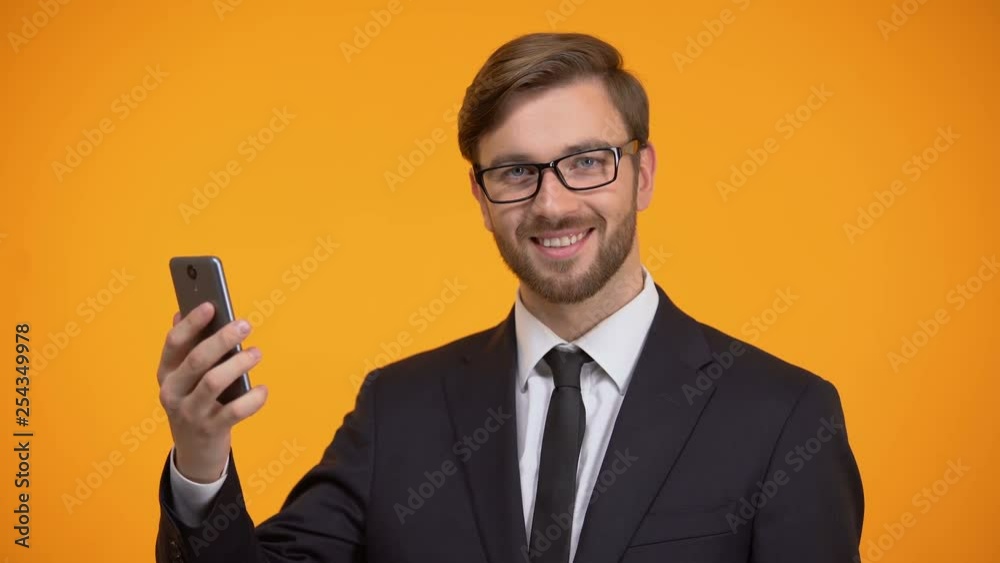 Male scrolling smartphone and smiling at camera, useful business application Male scrolling smartphone and smiling at camera, useful business application