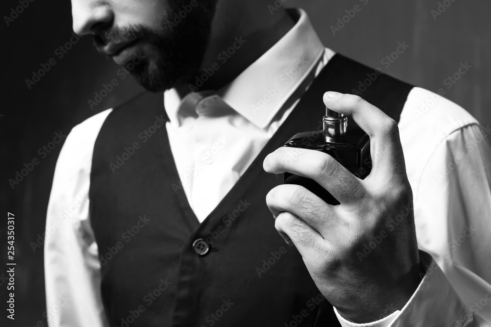 Handsome man with bottle of perfume on grey background, closeup - obrazy, fototapety, plakaty 