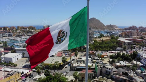 The Mexican flag blowing in the wind with Cabo San Lucas in the background photo