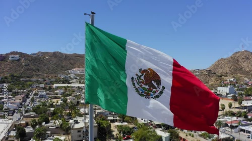 The Mexican flag blowing in the wind with Cabo San Lucas in the background photo
