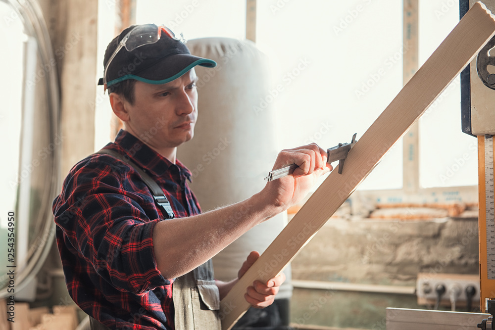 The worker makes measurements of a wooden board with corner ruler. The worker makes measurements of a wooden board with corner ruler.