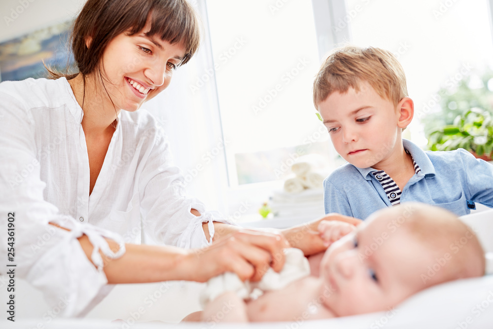 Junge schaut zu als Mutter das Baby badet