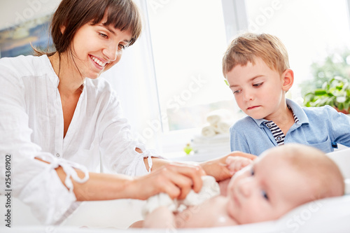 Junge schaut zu als Mutter das Baby badet