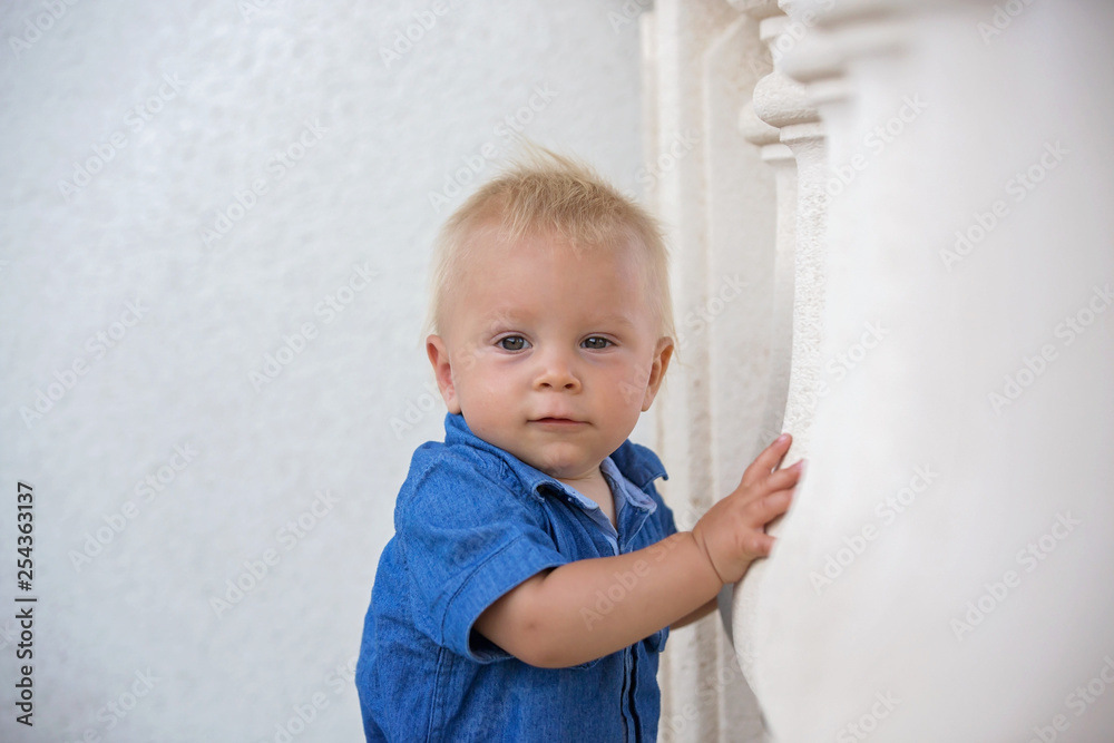 Naklejka premium Sweet toddler boy in garden, eating freshly baked scones with cream and jam