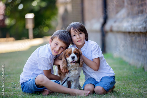 Beaugtiful preschool children, playing with sweet dog in the park