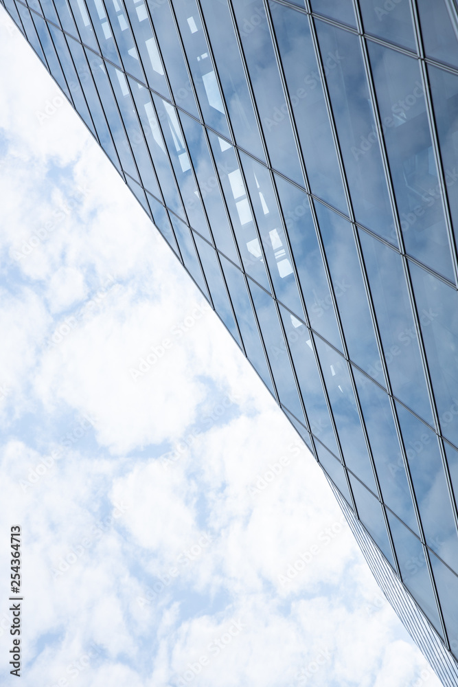 Fototapeta premium Cloud and sky reflected in the blue glass windows of building.