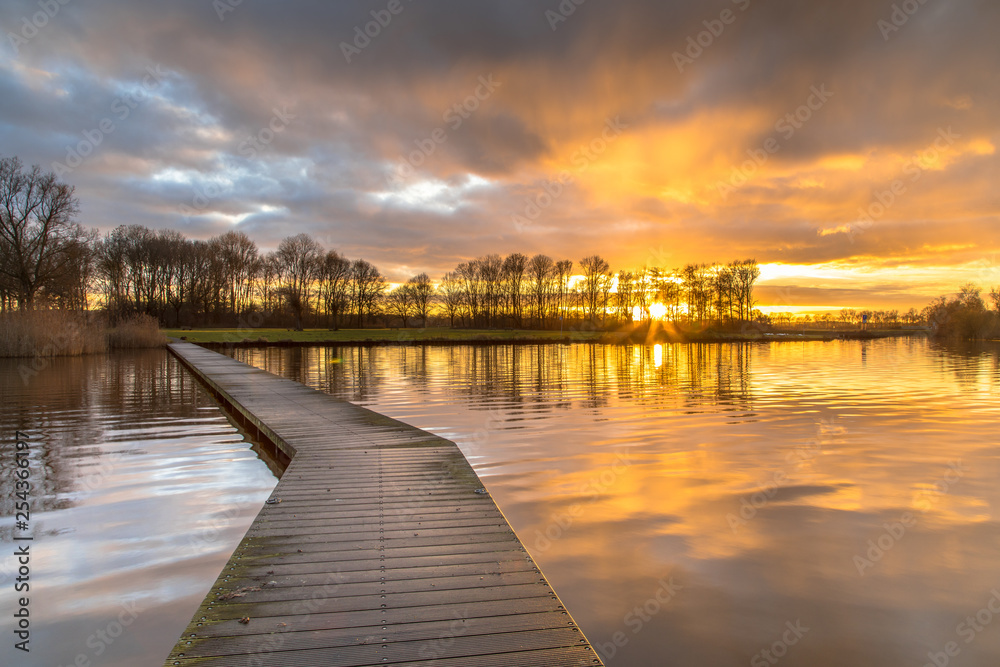Fototapeta premium Wooden walkway in lake under orange sunset