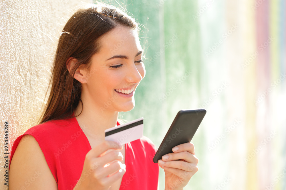Happy woman pays online with credit card and smart phone