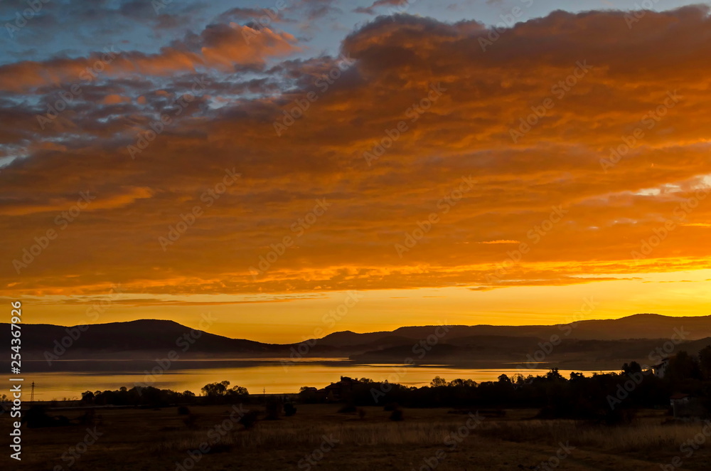 Obraz premium Mountain holiday village with sunrise in beauty yellow light around dam Batak, Tsigov chark resort, Rhodope mountains, Bulgaria
