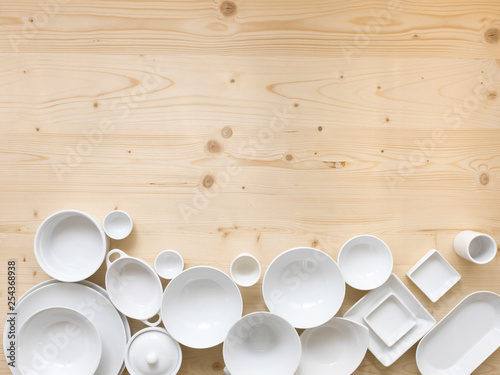 modern, white crockery, in different designs, stands on a light wooden background