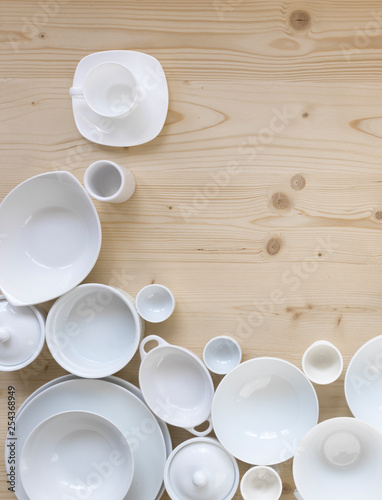 modern, white crockery, in different designs, stands on a light wooden background