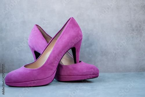 Bright pink high-heeled shoes on gray background.