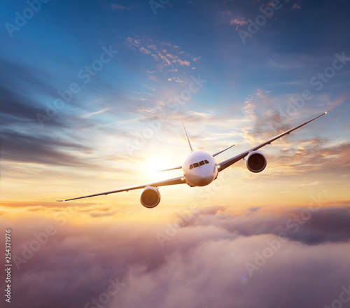 Commercial airplane flying over dramatic sunset