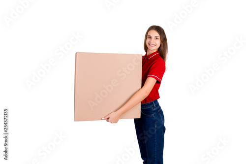 Beautiful girl is delivering a huge parcel to a customer. Smiling woman in work clothes is holding a box isolated on white background