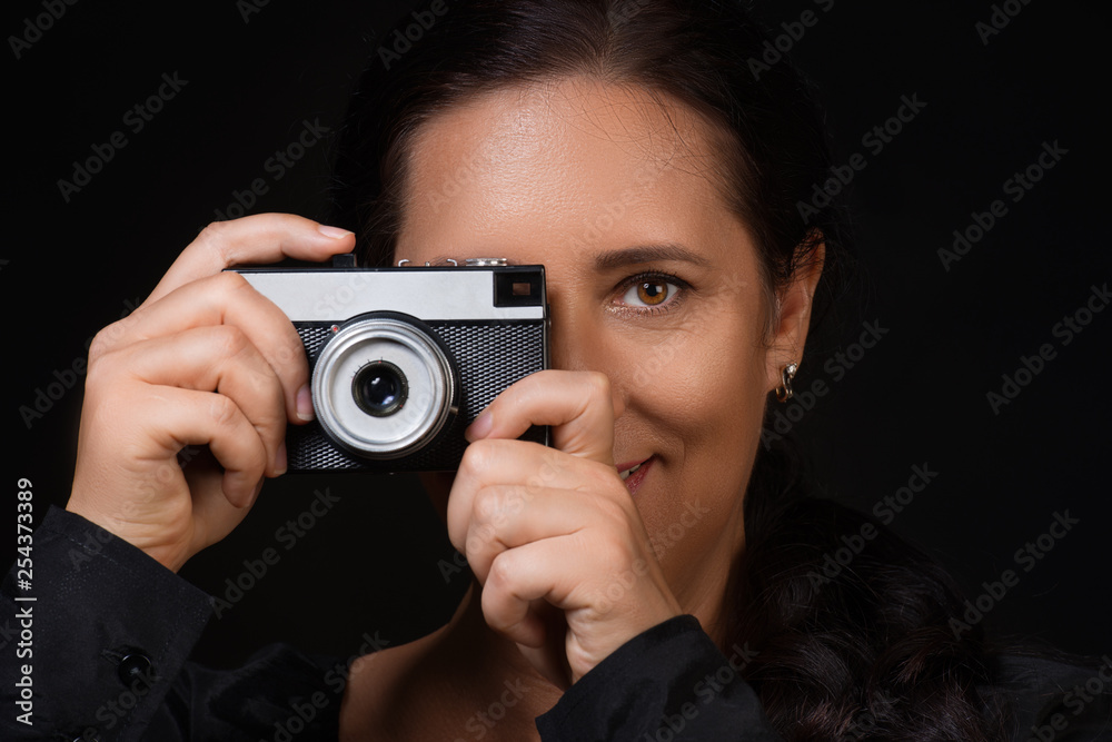 Close up portrait of a woman taking photo on a retro camera over black background Close up portrait of a woman taking photo on a retro camera over black background