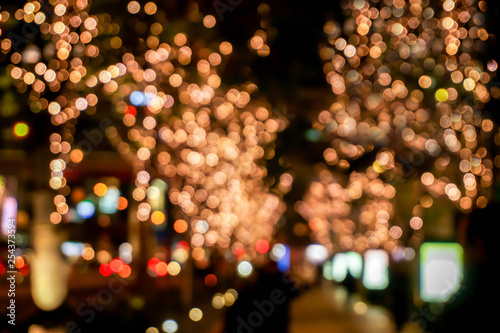 Blurred and bokeh of LED refection lighting decorate on trees with city night life in Osaka, Japan.