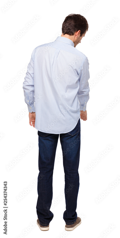 Back view of a man in jeans points his hand upwards.