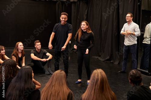 Teacher With Male And Female Drama Students At Performing Arts School In Studio Improvisation Class