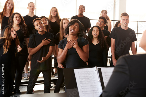 Male And Female Students Singing In Choir With Teacher At Performing Arts School photo