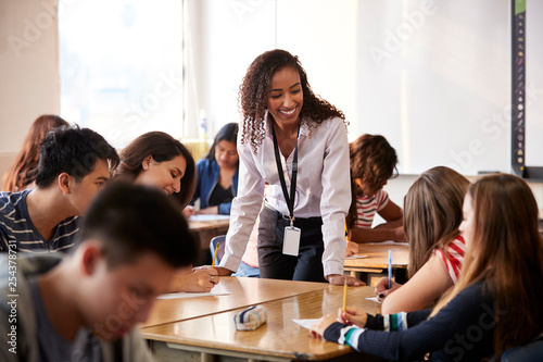 Photo Female High School Teacher Standing By Student Table Teaching Lesson