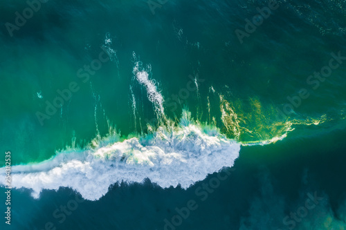 Looking down at crushing ocean wave at sunrise. Aerial view with copy space.