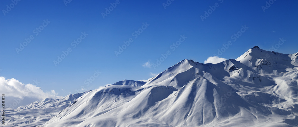 Panoramic view on snowy sunlit mountains