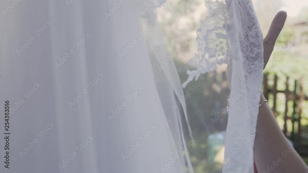 Excited bride touching and caressing her white wonderful wedding dress in a bright romantic light Excited bride touching and caressing her white wonderful wedding dress in a bright romantic light