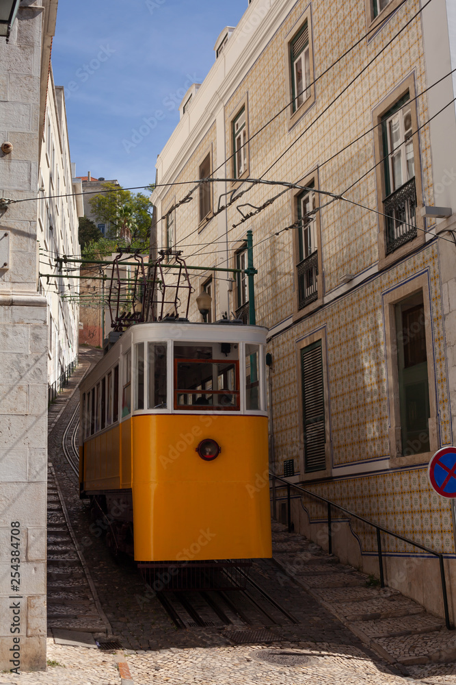 Fototapeta premium Yellow Lisbon tram on a narrow and steep street