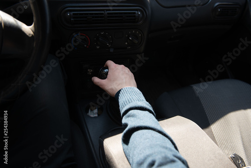 A man switches the speed on the gearbox in the car