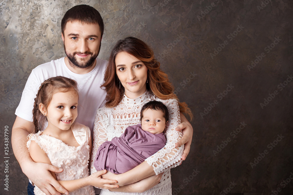 Happy family portrait.  Smiling parents with two children. Mother and father with newborn baby and toddler girl. Concept of  happy family. Copy space