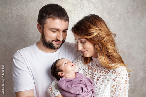 Woman and man holding a newborn. Mom, dad and baby. Portrait of smiling family with newborn on the hands. Happy family concept. Copy space